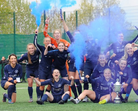 Women's football team celebrate with blue flares on an 4G football pitch.